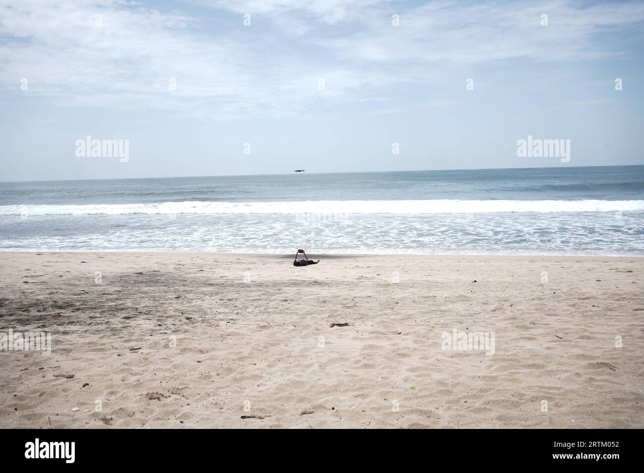 un touriste qui pilote un drone sur une plage de sable blanc pour des besoins de contenu. Banque D'Images