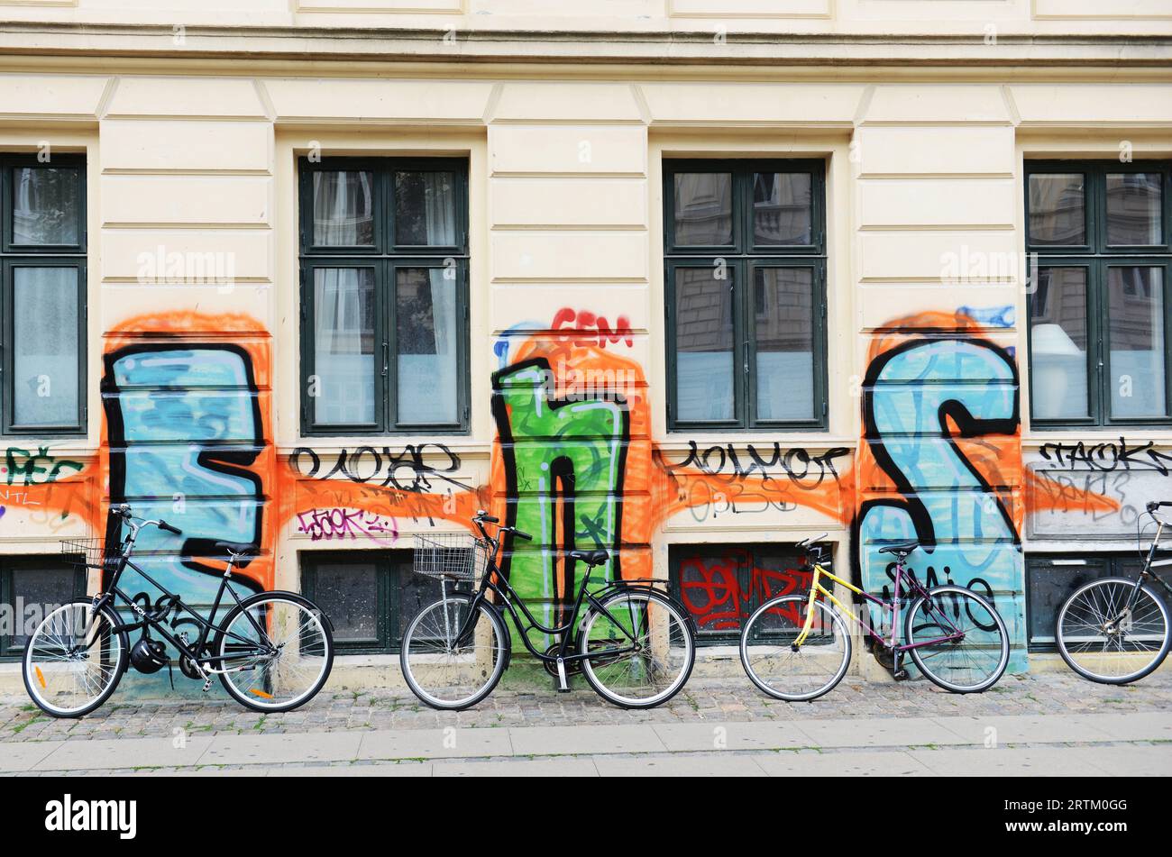 Vélos garés près d'un bâtiment couvert de graffitis moches à Copenhague, Danemark. Banque D'Images