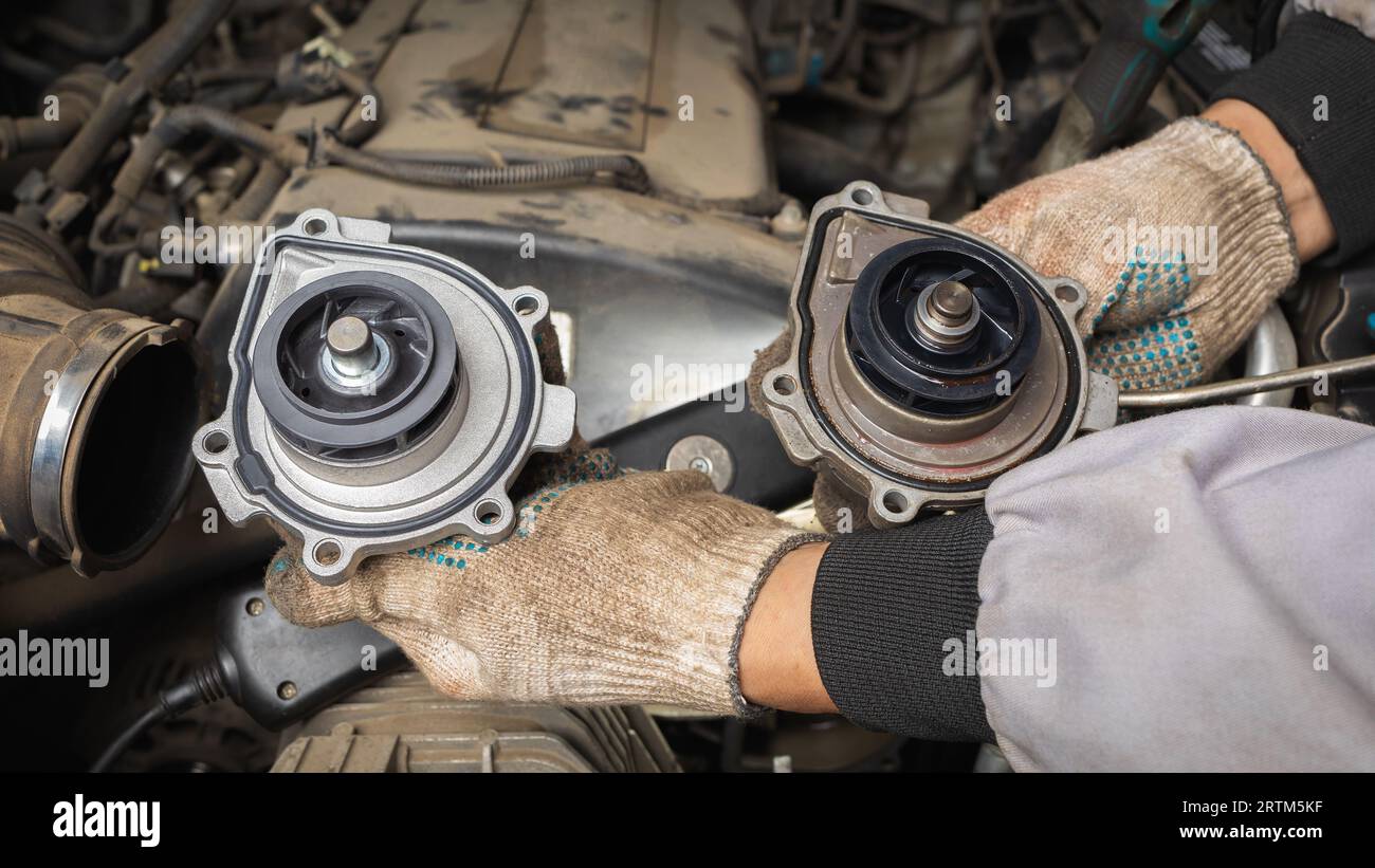 Un mécanicien automobile tient une pompe de moteur de voiture neuve et ancienne dans ses mains Banque D'Images