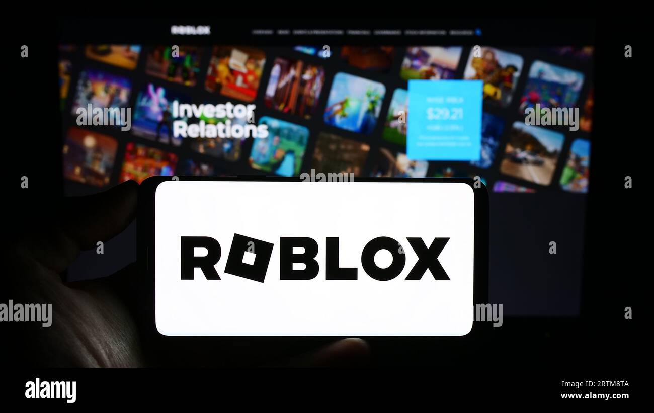 Personne tenant un smartphone avec le logo de la société américaine de jeux vidéo Roblox Corporation sur l'écran devant le site Web. Concentrez-vous sur l'affichage du téléphone. Banque D'Images