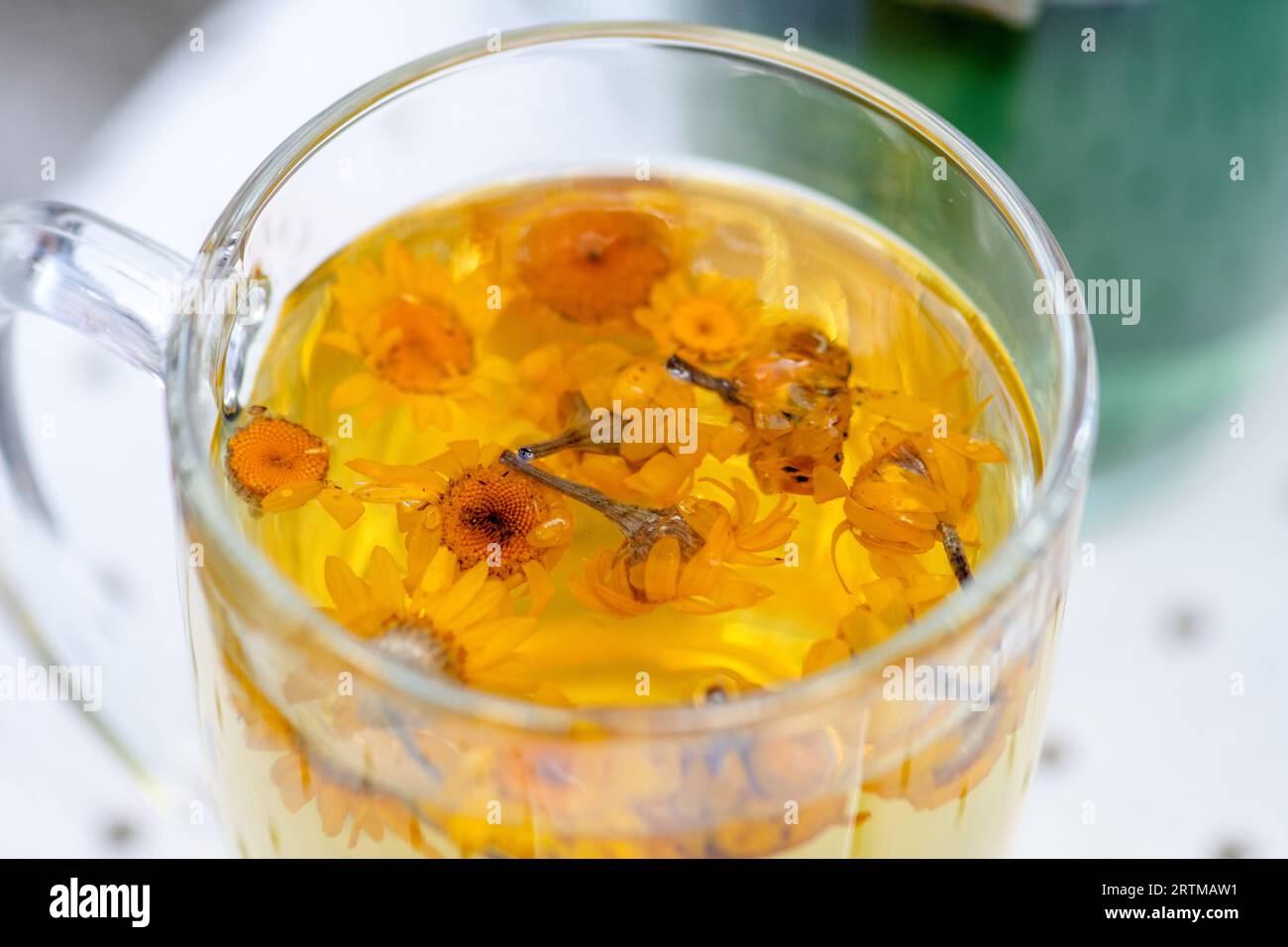 Tasse en verre avec de l'eau chaude et des fleurs de souci ou de calendula pour une infusion de tisane, gros plan Banque D'Images