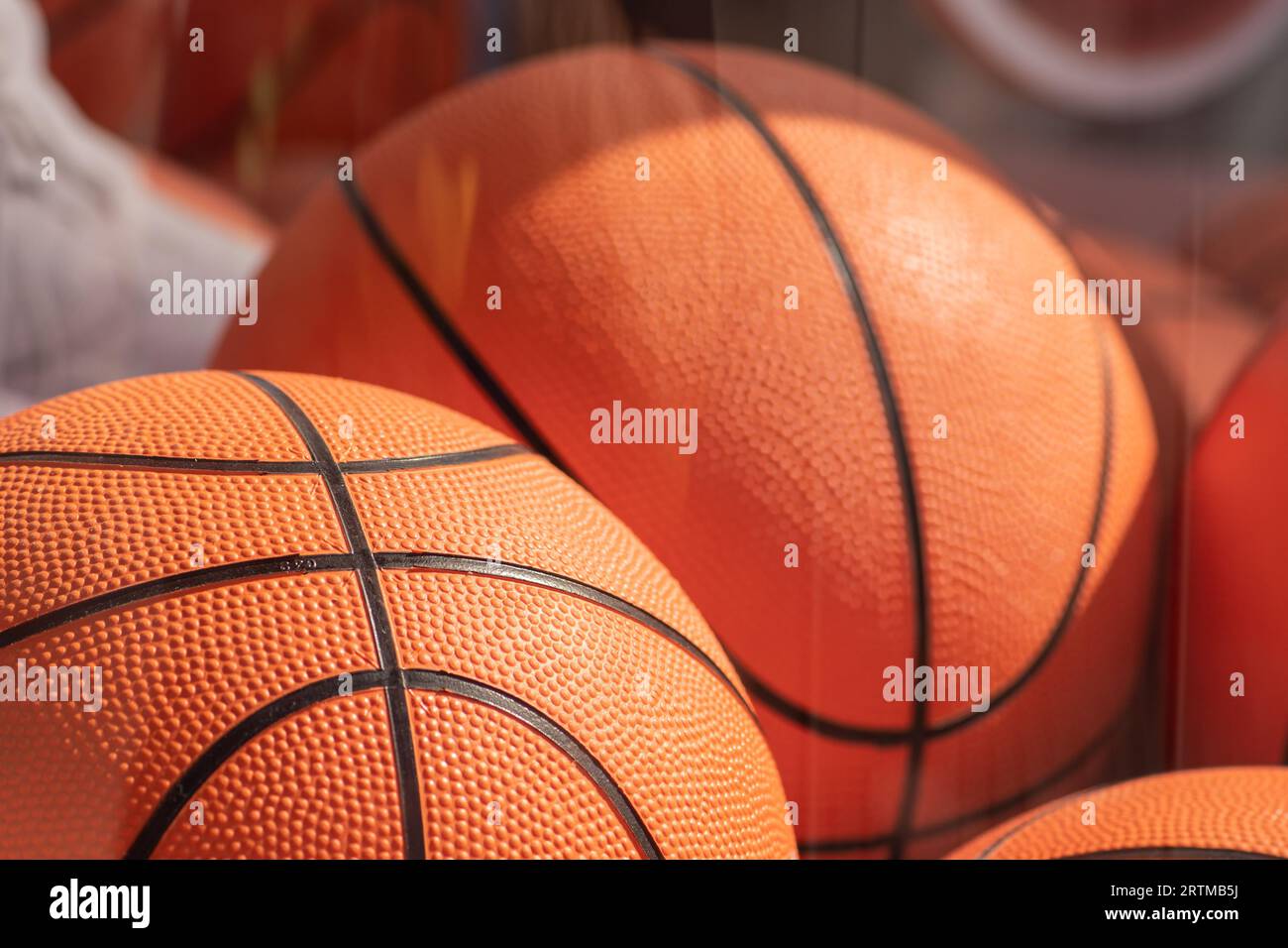 Beaucoup de balles de basket-ball orange dans une boîte en verre sous le soleil, en gros plan Banque D'Images
