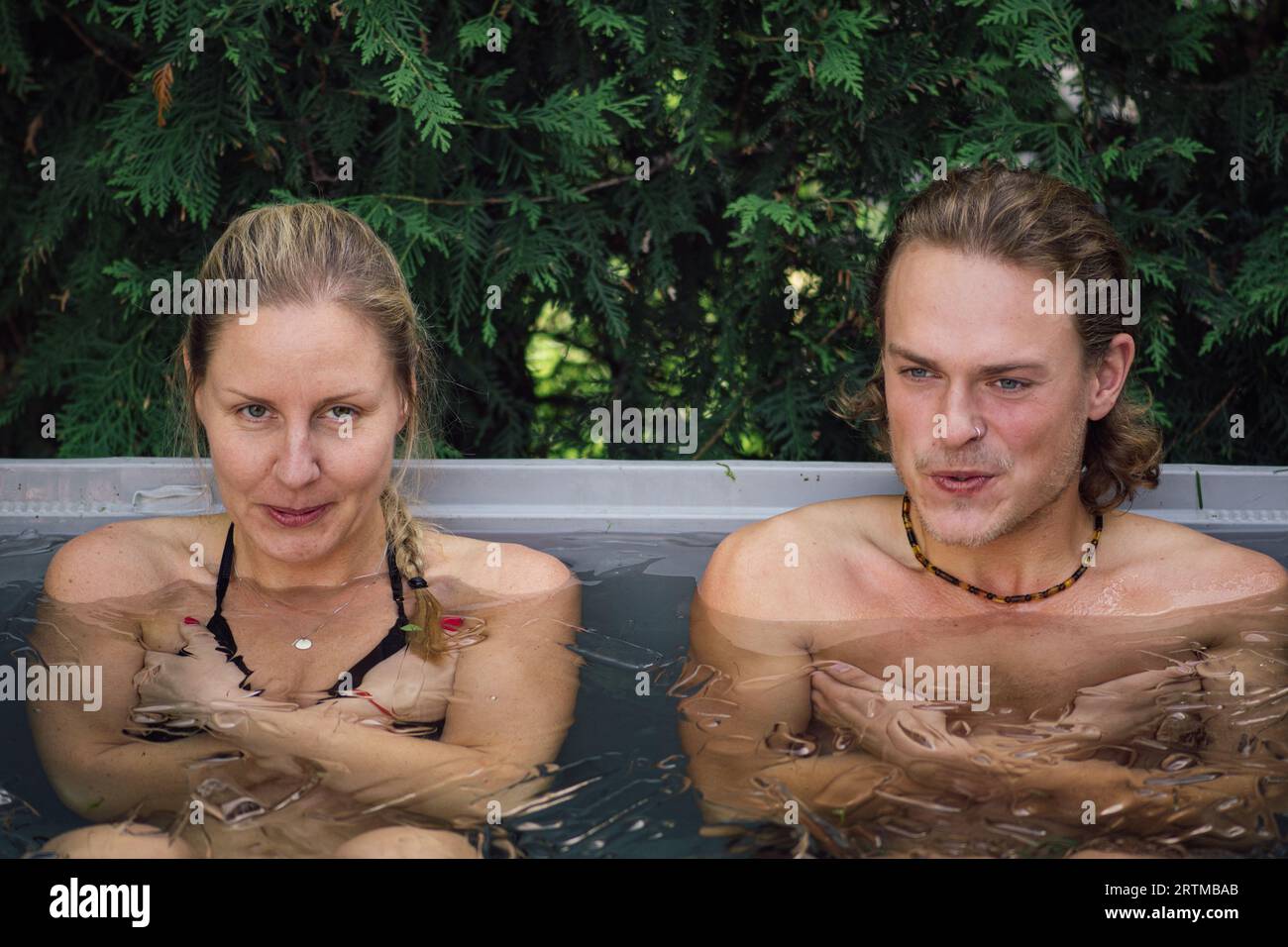 Beau jeune couple caucasien baignant dans l'eau froide parmi les glaçons. Méthode Wim Hof, thérapie par le froid, techniques de respiration, yoga, méditation Banque D'Images