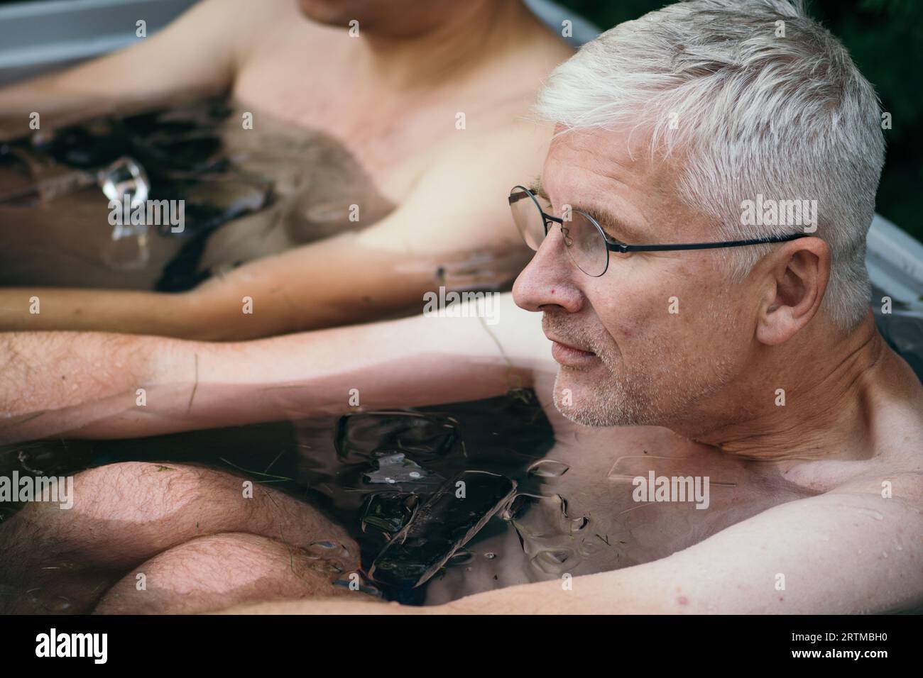 Homme adulte baignant de glace dans l'eau froide parmi les glaçons. Méthode Wim Hof, thérapie par le froid, techniques de respiration, yoga et méditation Banque D'Images