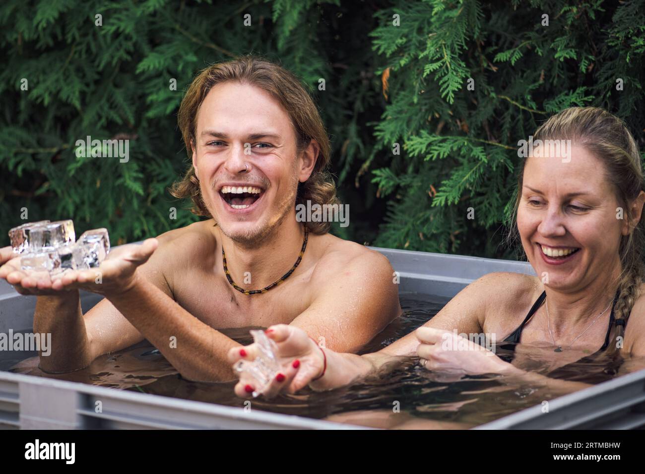 Beau jeune couple caucasien baignant dans l'eau froide parmi les glaçons. Méthode Wim Hof, thérapie par le froid, techniques de respiration, yoga, méditation Banque D'Images