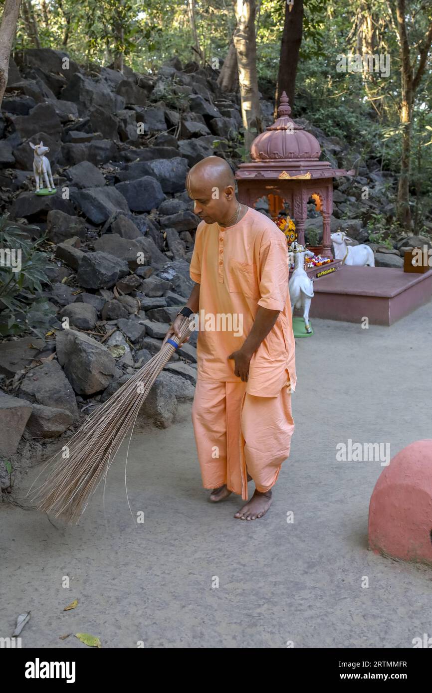Dévot balayant un temple forestier à Goverdan écovillage, Maharashtra, Inde Banque D'Images