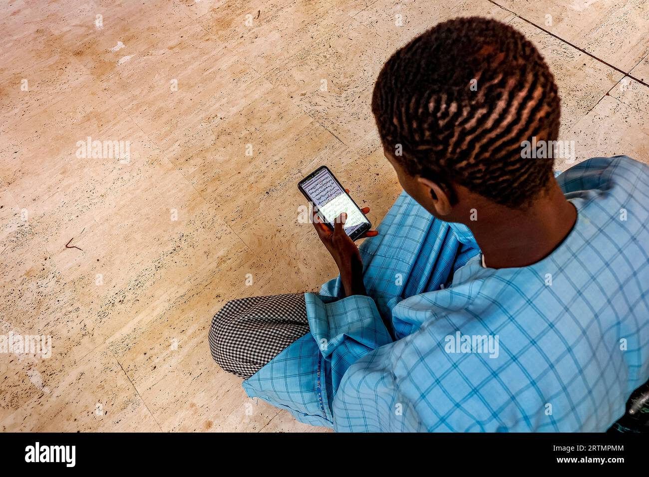 Musulman lisant les écritures coraniques sur son téléphone portable dans la grande mosquée de Touba, au Sénégal Banque D'Images
