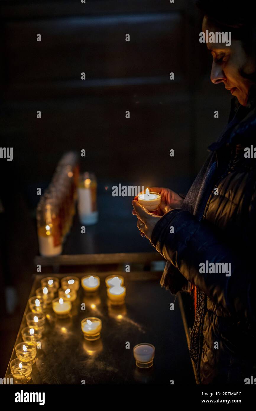 Femme tenant une bougie dans l'église catholique Saint-Nicolas, Bruxelles, Belgique. Banque D'Images