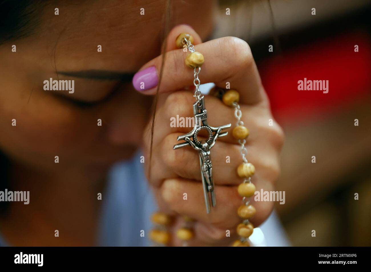 Femme catholique priant avec des perles de chapelet à la main. Femme catholique priant les perles du rosaire dans l'église. Porto. Portugal. Banque D'Images