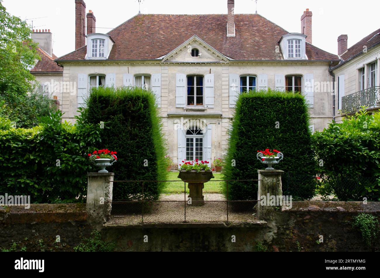 Bâtiment français traditionnel avec toit rouge et haie à l'avant. Crécy-la-Chapelle, France. Banque D'Images