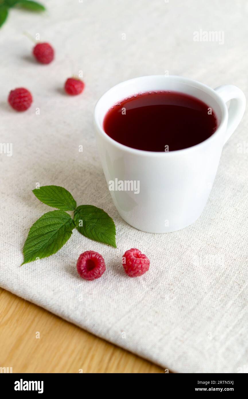 Compote de baies rafraîchissante douce de framboises mûres dans une tasse blanche, goût riche, couleur saturée. Boisson fraîche de saison Banque D'Images