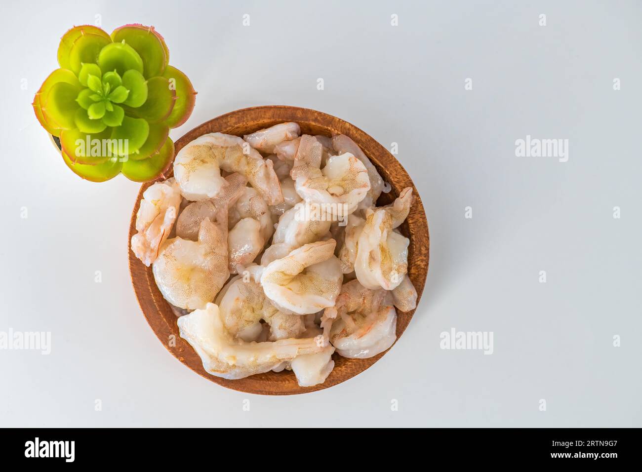 Crevettes crues fraîches nettoyées et conservées dans un bol en bois. Crevettes crues dans un bol en bois et isolées en fond blanc. Banque D'Images