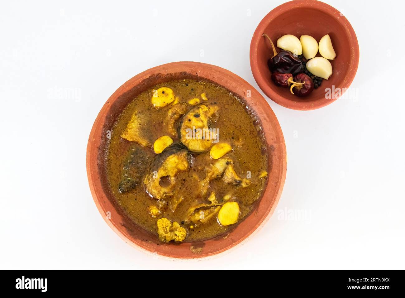 Curry de poisson servi dans un pot de boue traditionnel avec des ingrédients de curry de poisson. Curry de poisson frais avec piment, poivre et ail. Curry de poisson spécial de l'Inde du Sud. Banque D'Images