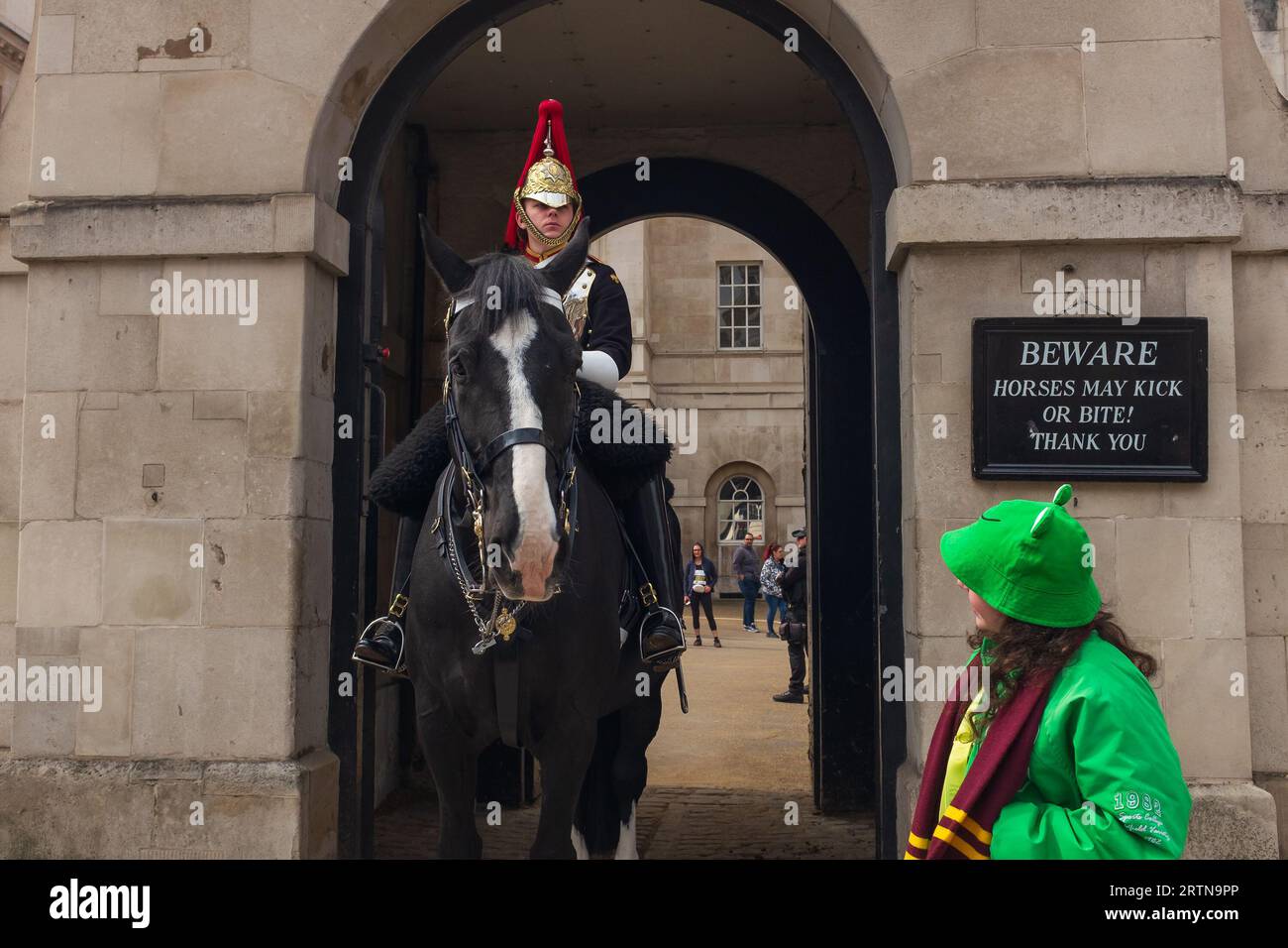 Londres, Royaume-Uni, 2023. Une jeune fille dans une tenue verte grenouille parle à un garde à cheval devant le Musée de la cavalerie de la maison sur la rue du Parlement Banque D'Images