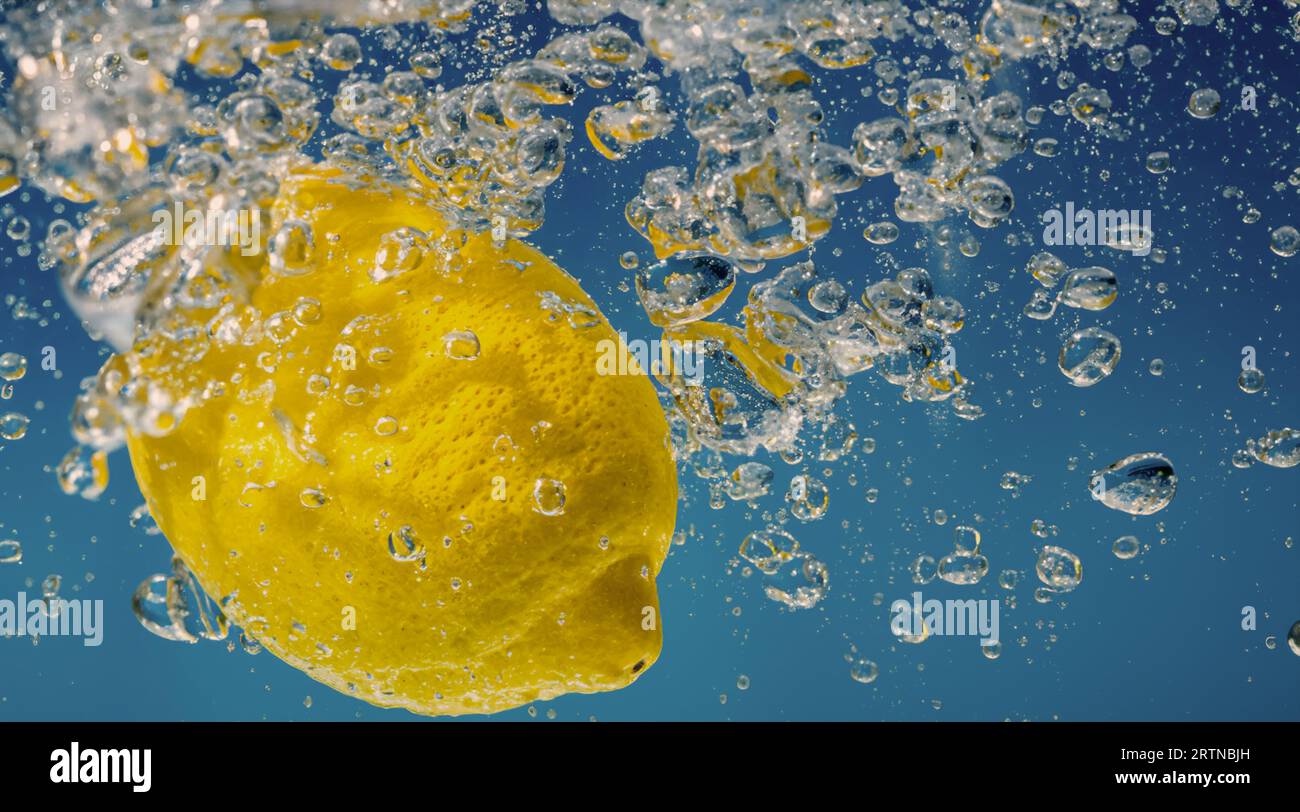 Tranche de citron sous-marine dans de l'eau gazeuse ou de la limonade avec des bulles. Cocktail rafraîchissant soda tonique pétillant. Gros plan de citrons et de glaçons en verre. Lime i. Banque D'Images