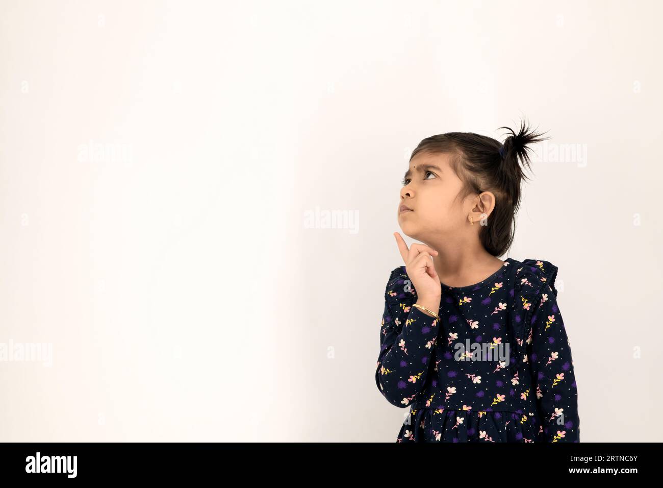 Belle petite fille réfléchie avec les yeux et le visage sérieux, pensant, hésitant ou ayant une idée ou une solution intelligente, avec fond blanc isolé Banque D'Images