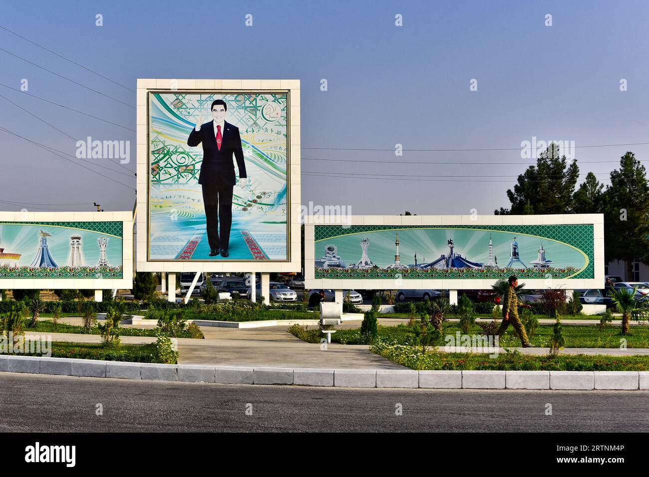 Militaire marchant devant une fresque de Berdymukhamedov et quelques-uns de ses projets déterminants pour sa carrière/éléphants blancs, Achgabat, Turkménistan, octobre 2017 Banque D'Images