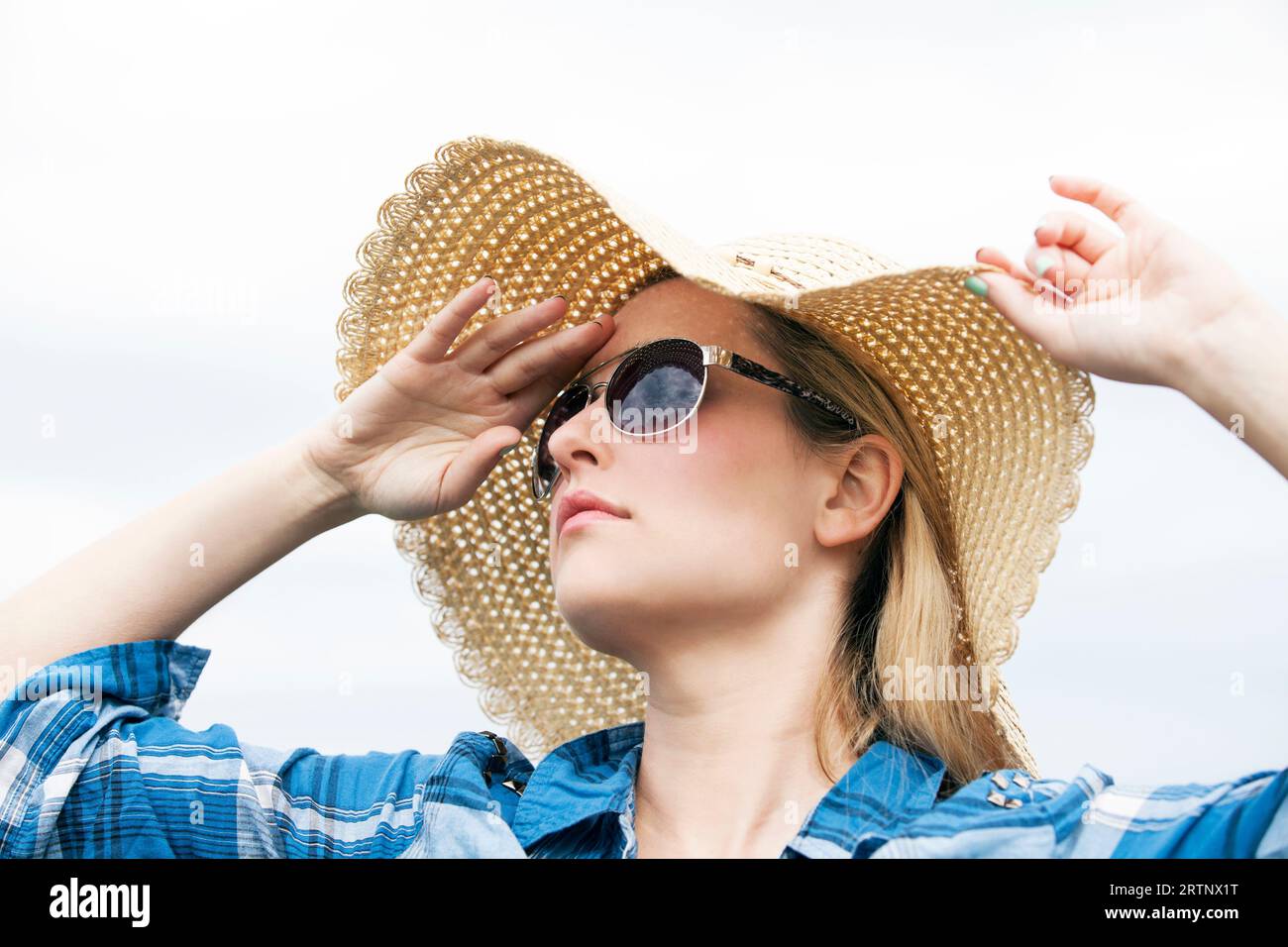 jeune femme regardant dans la distance avec des lunettes de soleil et chapeau de soleil sur Banque D'Images