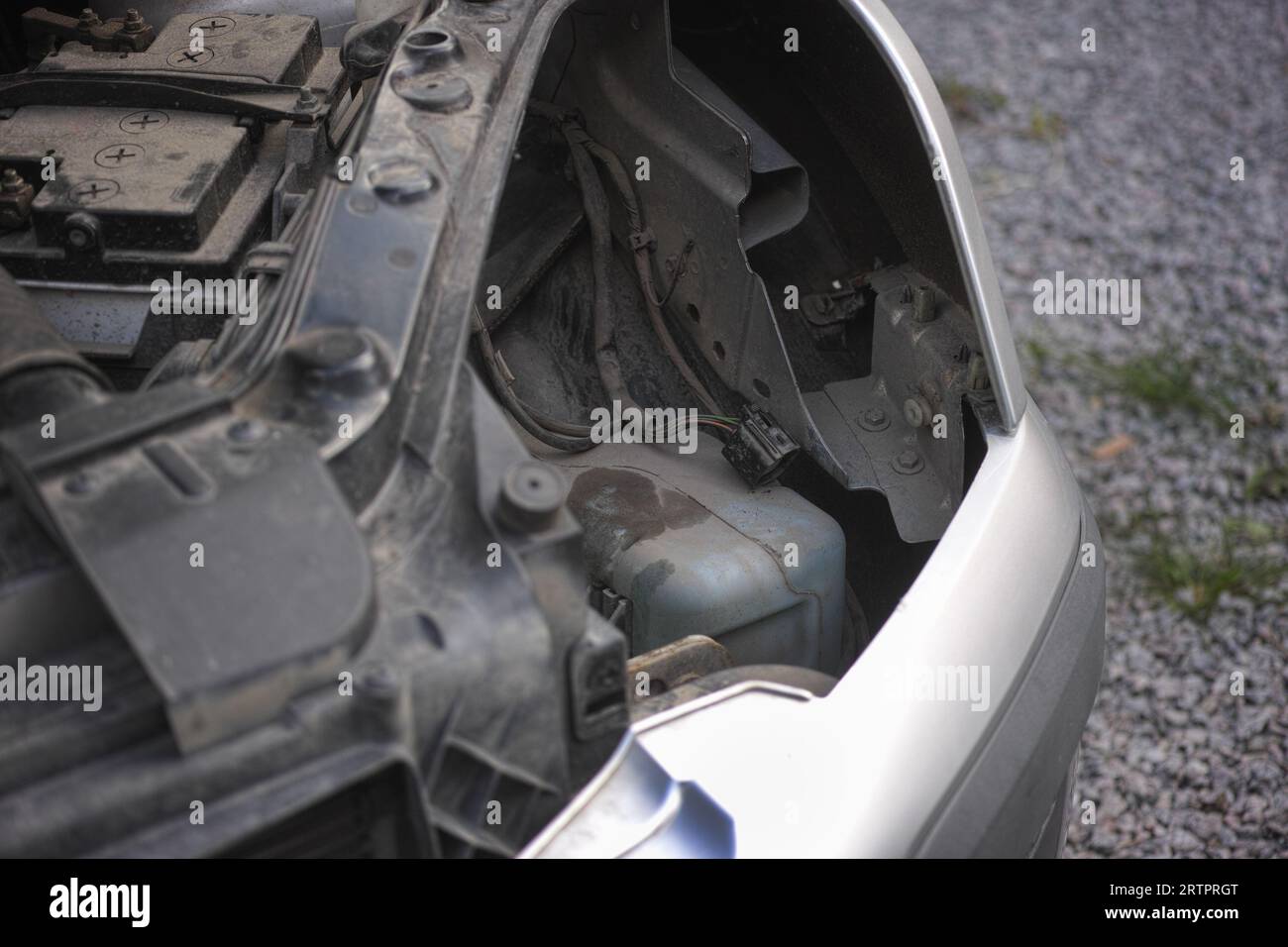 Une voiture avec un phare enlevé et un capot ouvert debout sur une allée rocheuse. Gros plan. Banque D'Images