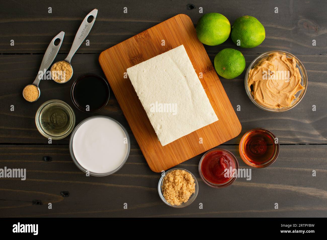 Satay au tofu avec sauce arachide Ingrédients sur une table en bois : caillé de haricot entouré de citrons verts, de beurre d'arachide et d'autres ingrédients pour un apéritif végétalien Banque D'Images