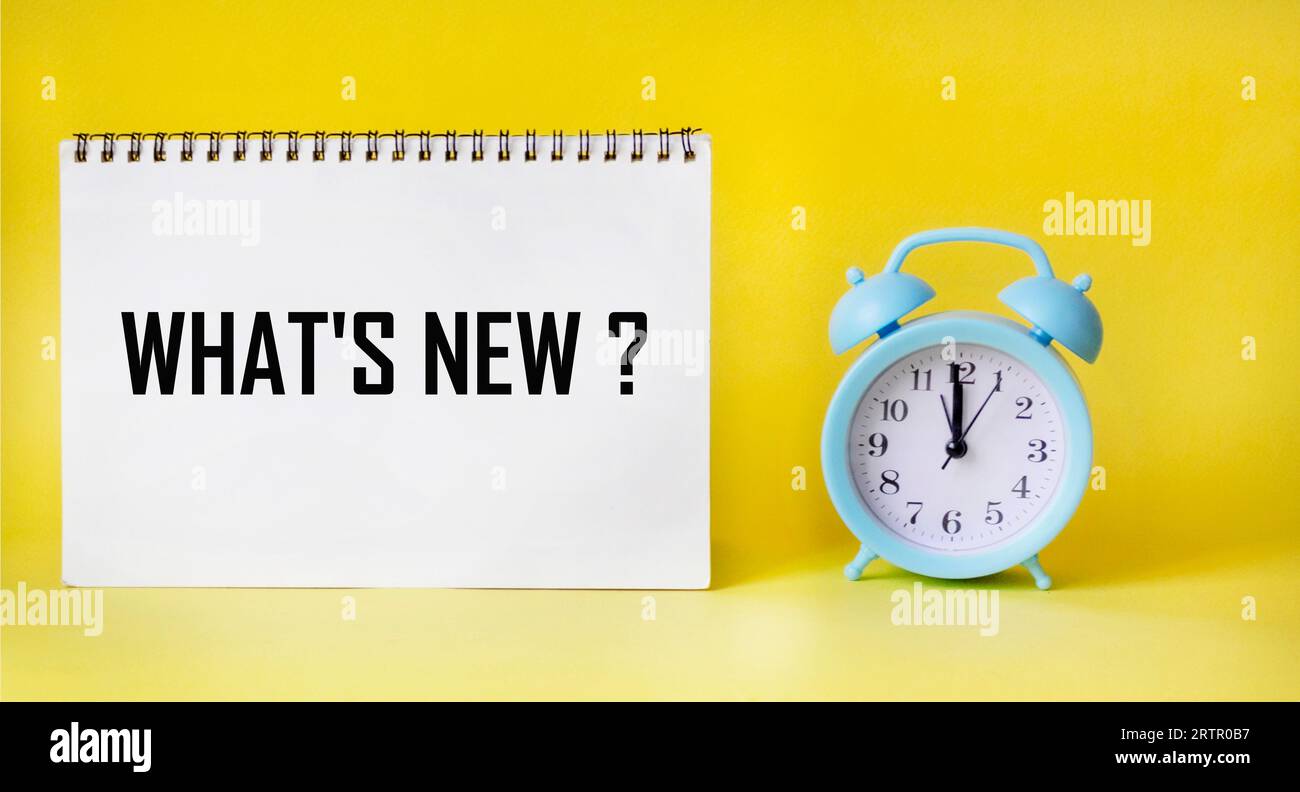 Panneau texte Quoi de neuf, sur un bloc-notes et un fond jaune avec une horloge Banque D'Images