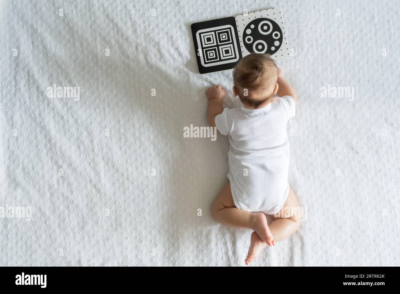 Un bébé regarde un livre éducatif contrasté noir et blanc. Le développement intellectuel du nouveau-né. Développer des cartes pour enfants. Banque D'Images