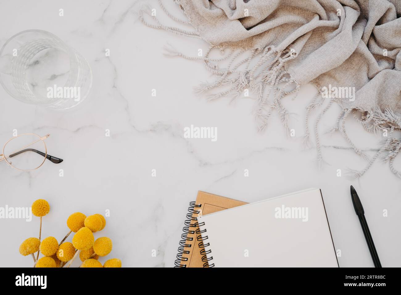 Mise à plat de cahier blanc avec espace de copie pour le texte, les verres et les fleurs jaunes sur fond de marbre blanc. Vue de dessus. Bureau à domicile minimal. Travail o Banque D'Images