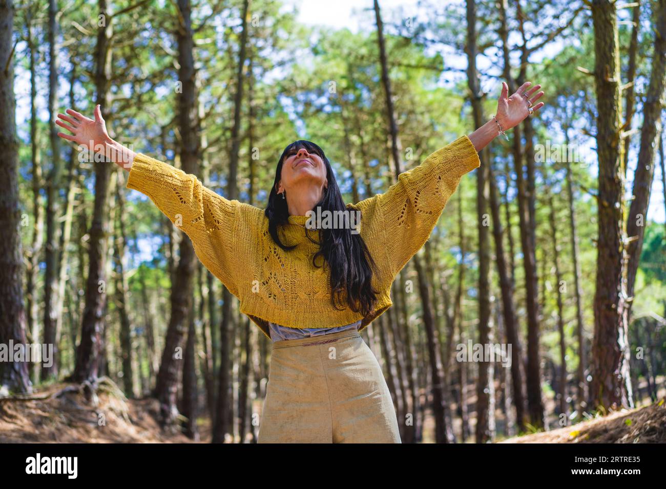 Femme avec les bras ouverts regardant vers le haut tout en profitant de la nature. Concept de liberté. Banque D'Images