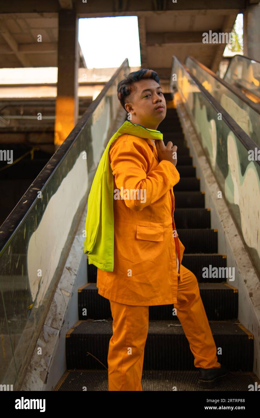 Un asiatique en costume jaune se tient debout sur un ascenseur cassé dans la journée Banque D'Images
