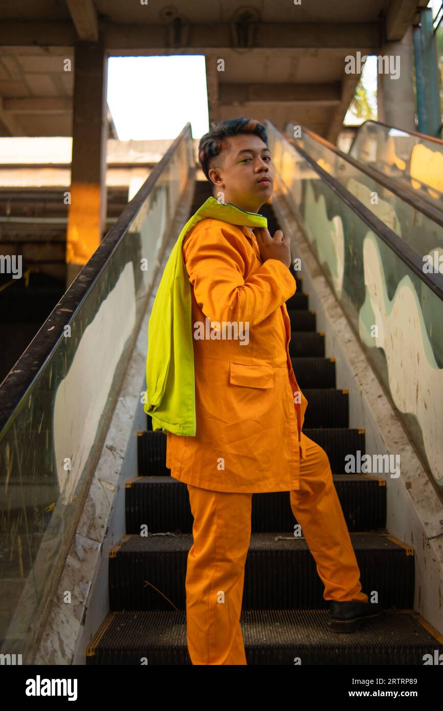 Un asiatique en costume jaune se tient debout sur un ascenseur cassé dans la journée Banque D'Images