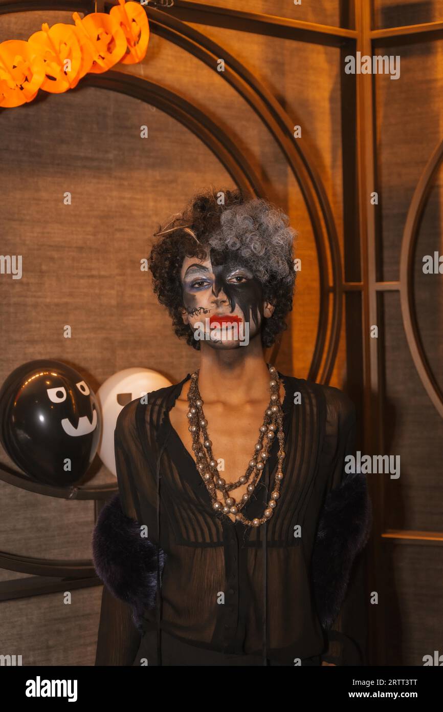 Fête d'Halloween avec des amis dans une discothèque, portrait d'un homme avec son visage peint en noir et blanc Banque D'Images