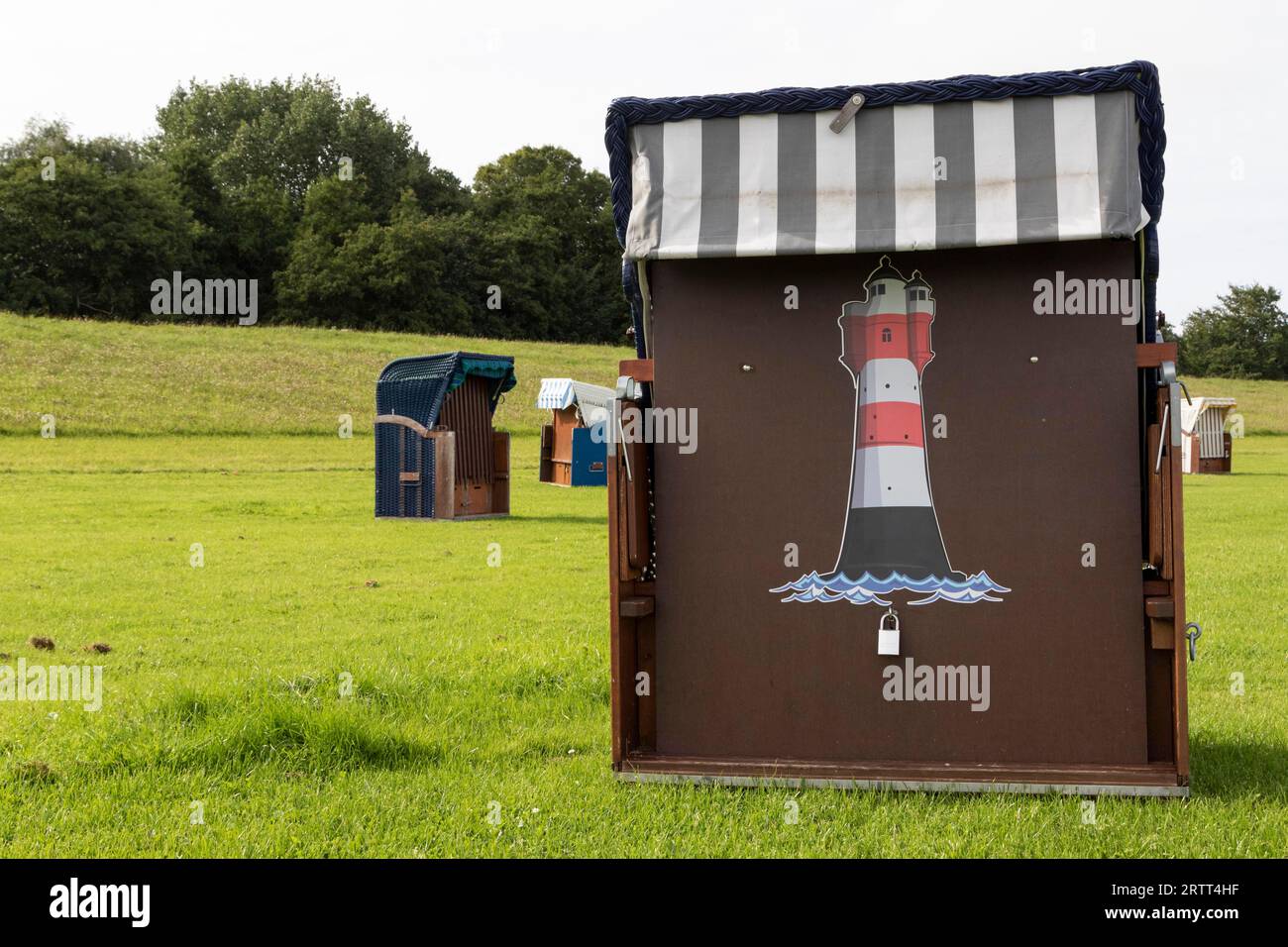 Chaise de plage avec peinture de phare sur une prairie verte à la plage de Cuxhaven, côte de la mer du Nord, Basse-Saxe, Allemagne Banque D'Images
