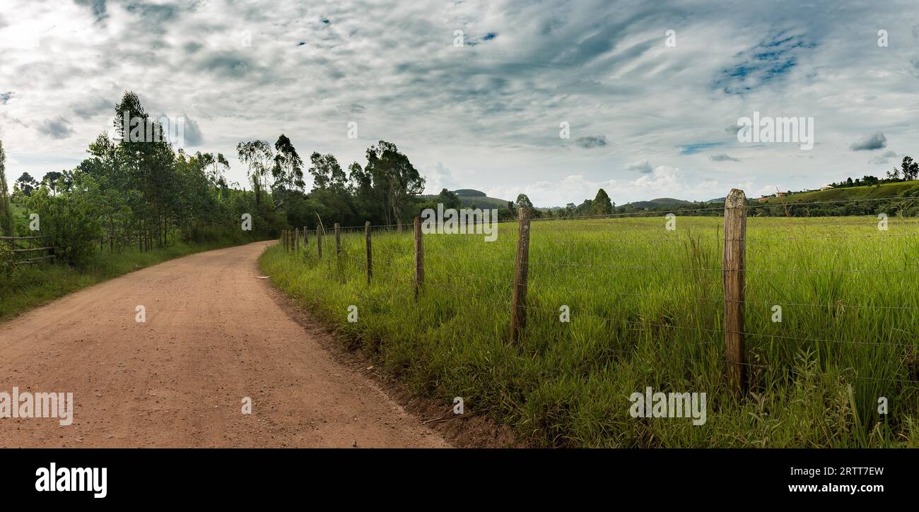 Chemin de terre et barbelés sur l'après-midi d'été dans les montagnes de Minas Gerais, Brésil Banque D'Images