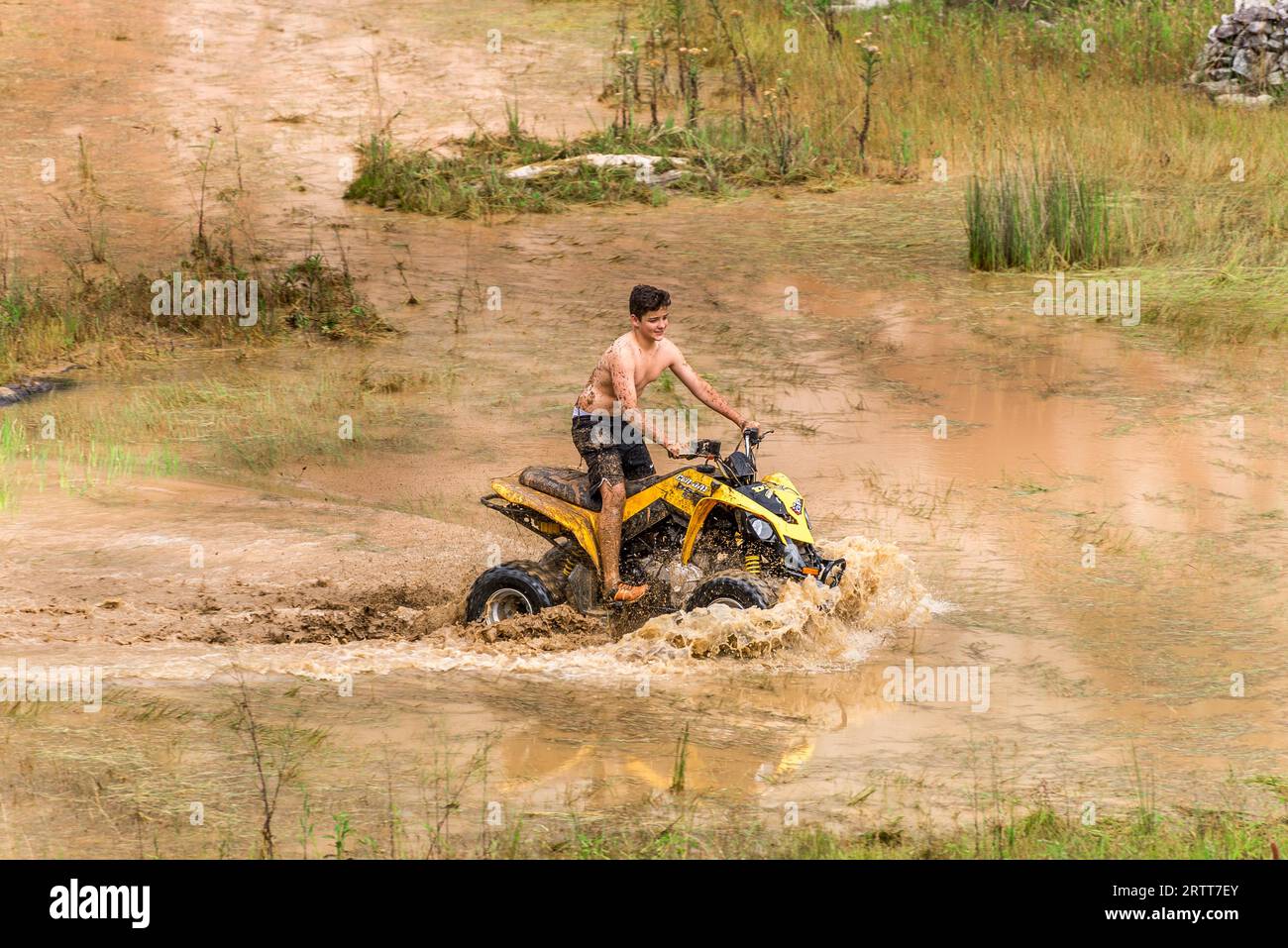 Minas Gerais, Brésil, 27 décembre 2015 : Homme dans la nature sortir de la route sur un rallye quad sur une flaque de boue dans la campagne Banque D'Images