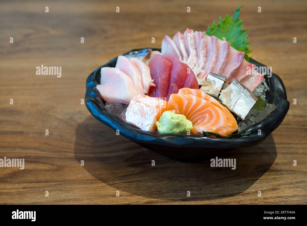 Un spectacle alléchant de sashimi japonais, élégamment servi dans un bol immaculé, reposant sur une table en bois rustique. Découvrez les couleurs éclatantes et de Banque D'Images