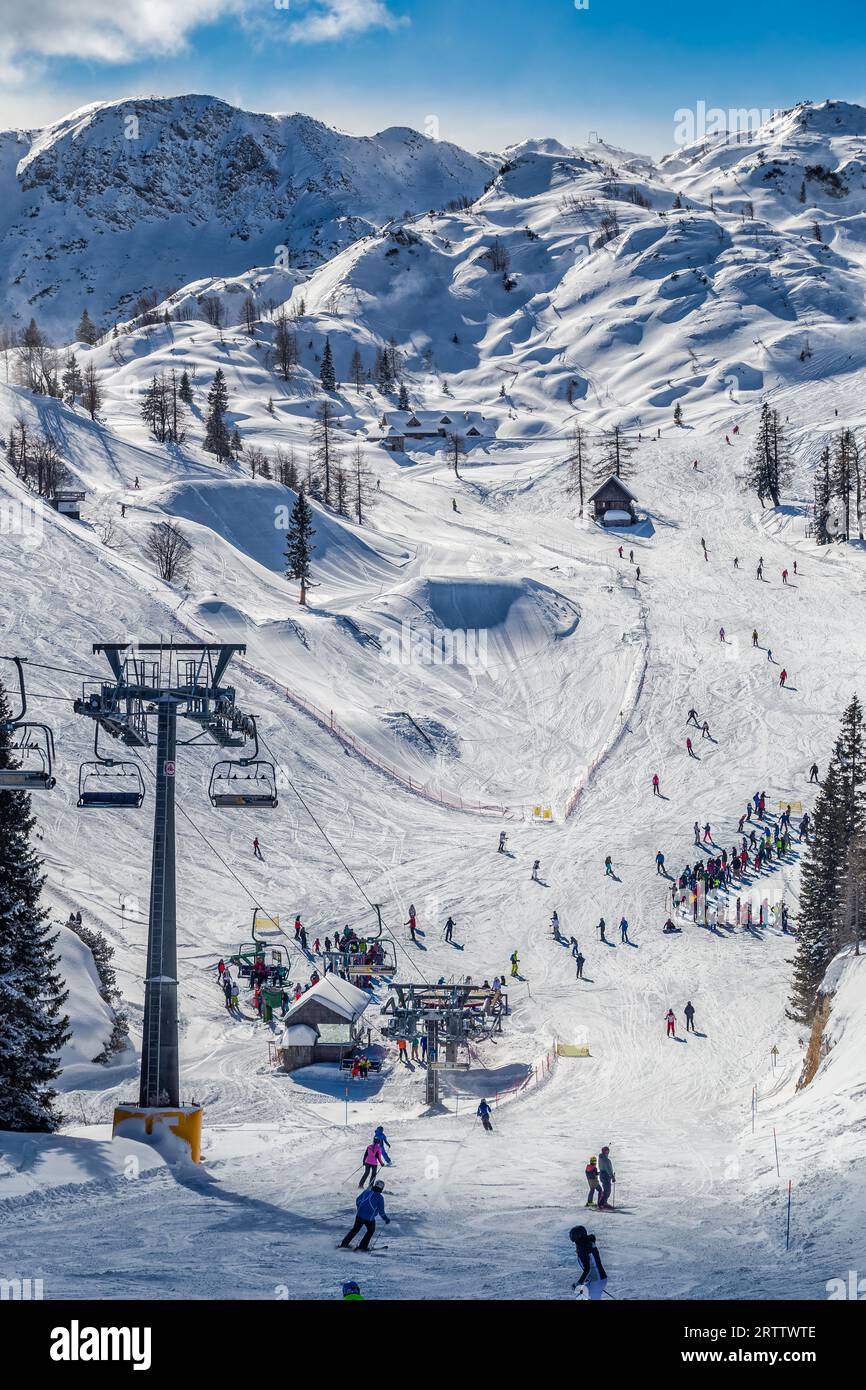 Bohinj, Slovénie - vue hivernale de la montagne enneigée de Vogel avec des skieurs sur les pistes de ski et remontées mécaniques dans les Alpes au parc national du Triglav sur une winte ensoleillée Banque D'Images