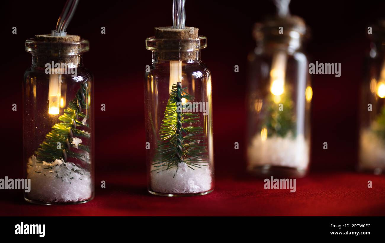 Guirlande lumineuse de Noël créative avec bokeh. Arbre de Noël dans un bocal en verre avec de la neige. Carte de voeux de Noël. Banque D'Images