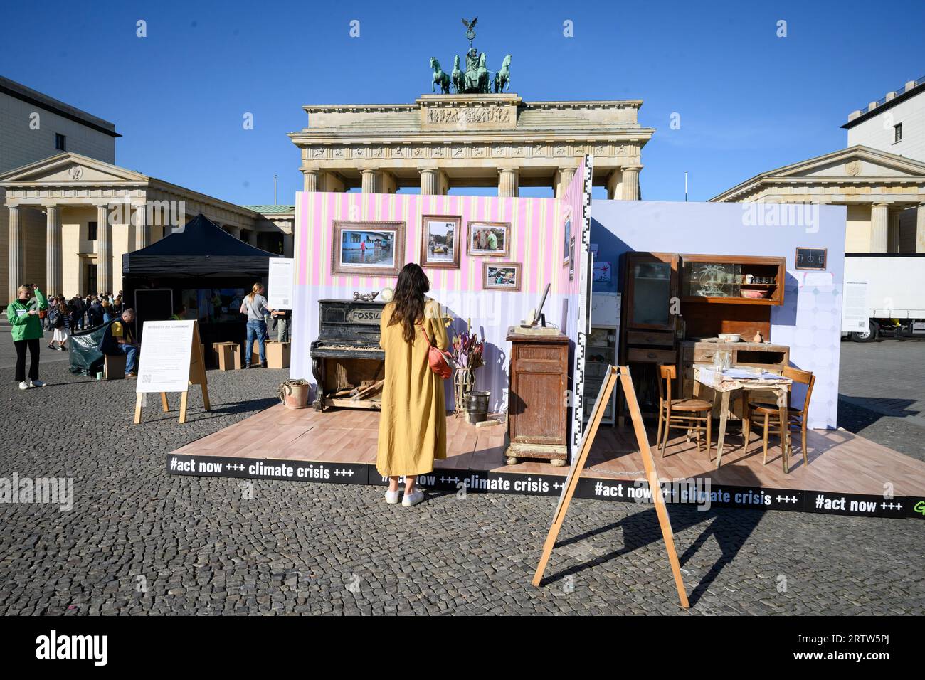 15 septembre 2023, Berlin : les passants regardent une réplique d'un appartement endommagé par les inondations devant la porte de Brandebourg, que Greenpeace utilise pour protester pour plus de protection du climat à l'occasion de la grève mondiale sur le climat. Le logement inondé se compose de meubles et d'accessoires boueux d'origine provenant des zones inondées de la région italienne d'Emilie-Romagne et de la vallée de l'Ahr. Greenpeace appelle le gouvernement allemand à fournir un soutien financier aux mesures d’adaptation au changement climatique, à éliminer progressivement les combustibles fossiles plus rapidement et à atteindre les objectifs gouvernementaux de protection du climat. Photo : Bernd von Banque D'Images