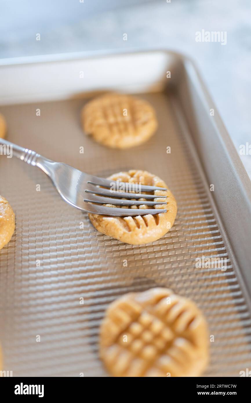 Une fourchette pressant des biscuits au beurre d'arachide sur une plaque de cuisson Banque D'Images