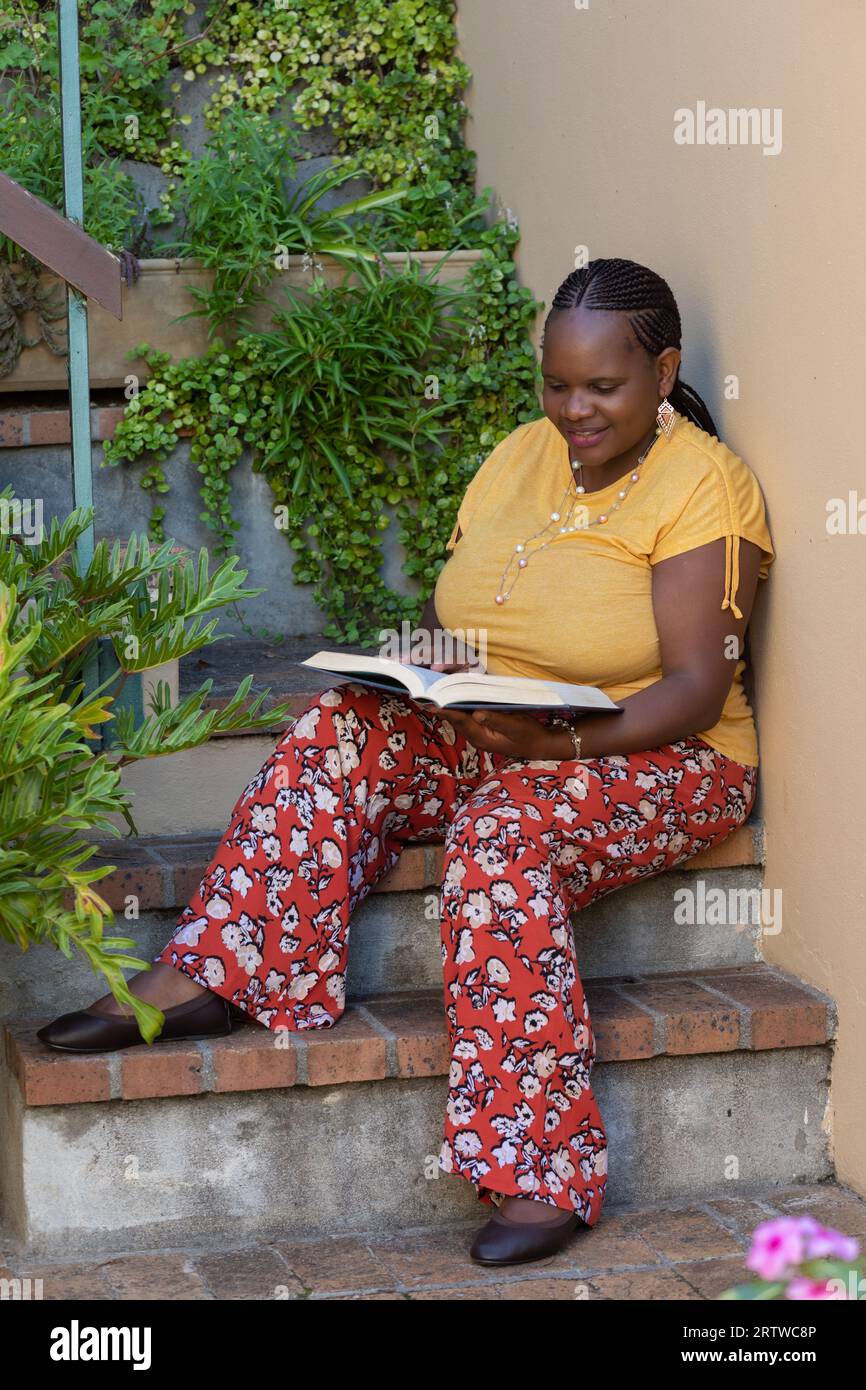 Portrait d'une jeune femme noire lisant un livre en plein air Banque D'Images