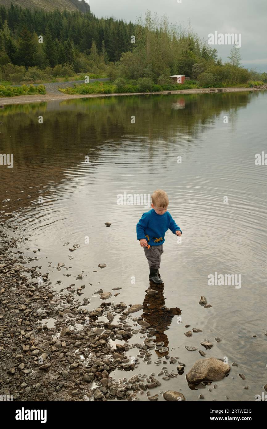 Petit garçon marchant sur la rive du lac Banque D'Images