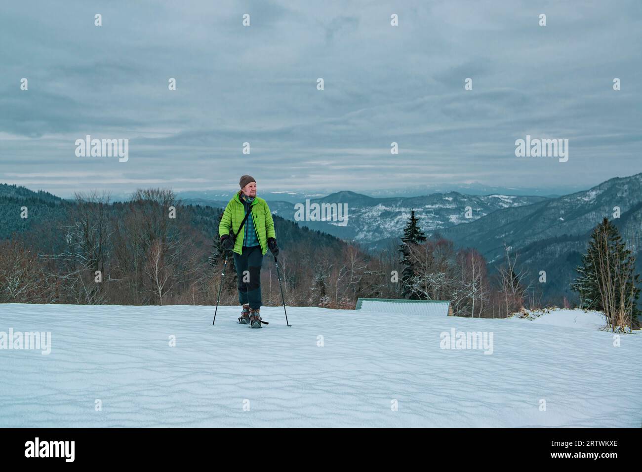Homme randonneur solitaire avec des raquettes de neige et des bâtons de trekking marche sur le champ de neige haut dans les montagnes d'hiver Banque D'Images