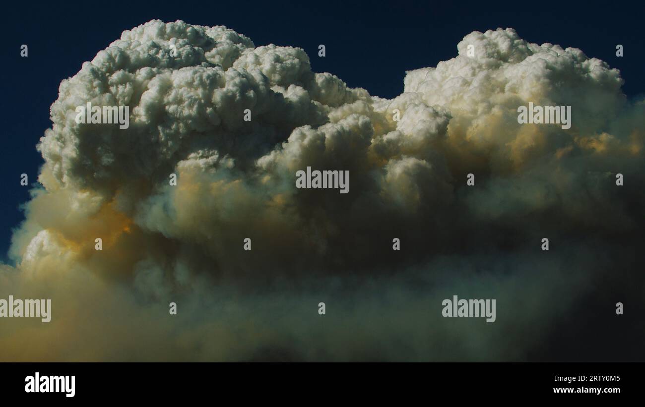 Les nuages de Pyrocumulus étouffés par la cendre et la fumée menacent le ciel bleu terriblement calme. Banque D'Images