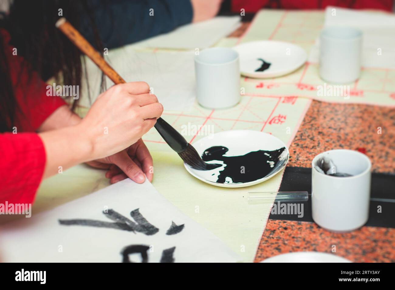 Leçon de calligraphie chinoise, groupe d'enfants apprennent et pratiquent la calligraphie traditionnelle en classe, enfant noir à l'encre et au pinceau apprendre l'écriture du chinois Banque D'Images