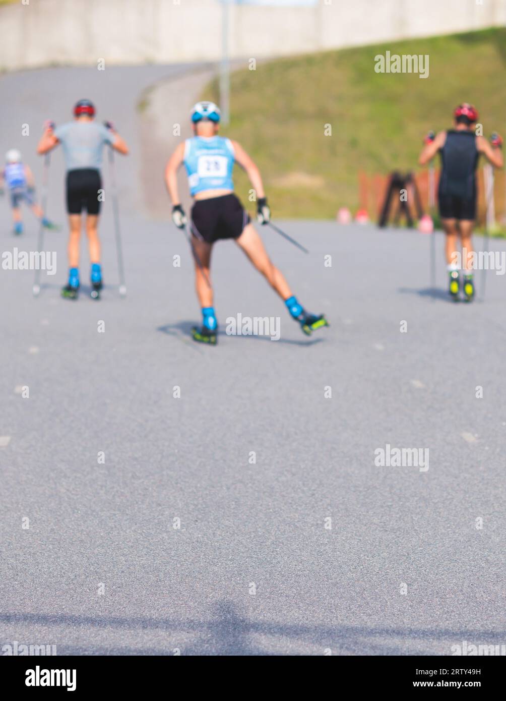 Les athlètes font du roller skis sur piste asphaltée, groupe de rollers de ski en casque, ski de fond avec roller ski dans une journée ensoleillée d'été, les sportifs skient- Banque D'Images