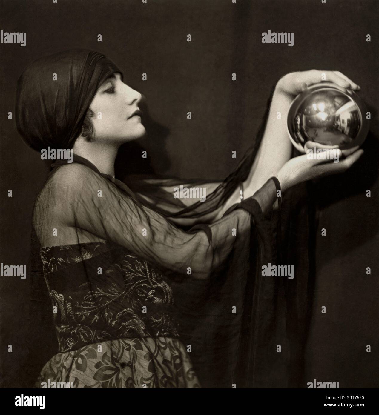 Londres, Angleterre c. 1920. L'actrice de cinéma muet Manora (aka Manvia) regarde le mystique dans une boule de cristal qu'elle tient dans ses mains. Photographie d'Emil Otto Hoppe. Banque D'Images