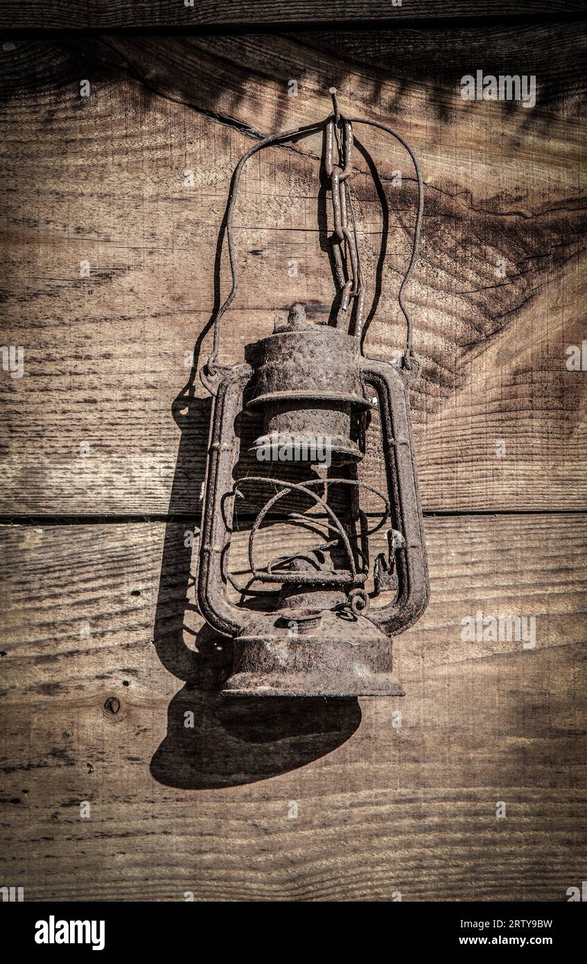 Vieille lampe à huile cassée rouillée accrochée au mur de cabane en bois Banque D'Images