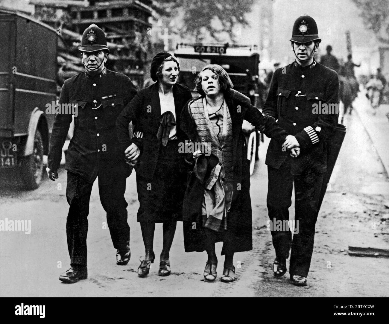Londres, Angleterre c. 1931 la police montée et les sympathisants des chômeurs se sont affrontés lors d'une manifestation devant le Parlement aujourd'hui. Ces deux filles ont été arrêtées par la police au plus fort de la manifestation. Banque D'Images