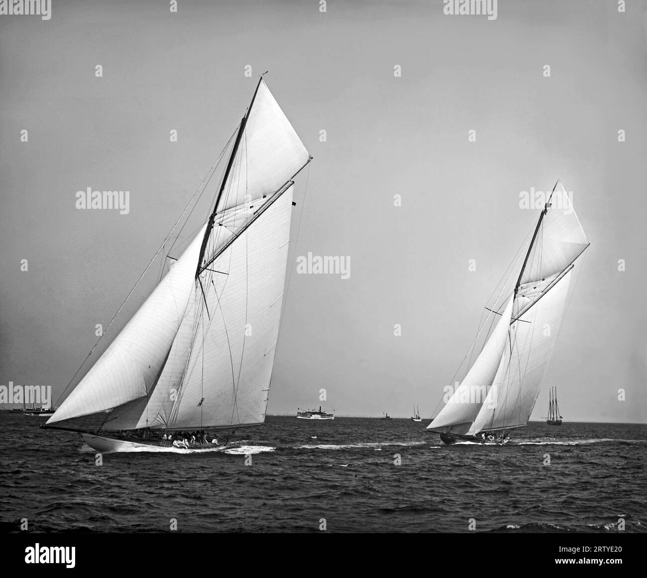 New York, New York 1901 Yachts “Columbia” et “Shamrock II” attendent le départ des courses de la coupe de l’America 1901 dans le port de New York. Columbia, représentant le New York Yacht Club, et Shamrock II, représentant le Royal Ulster Yacht Club, se sont affrontés dans cinq séries de courses. « Columbia » a remporté le titre pour la deuxième année consécutive, établissant un nouveau record de victoires consécutives. Banque D'Images