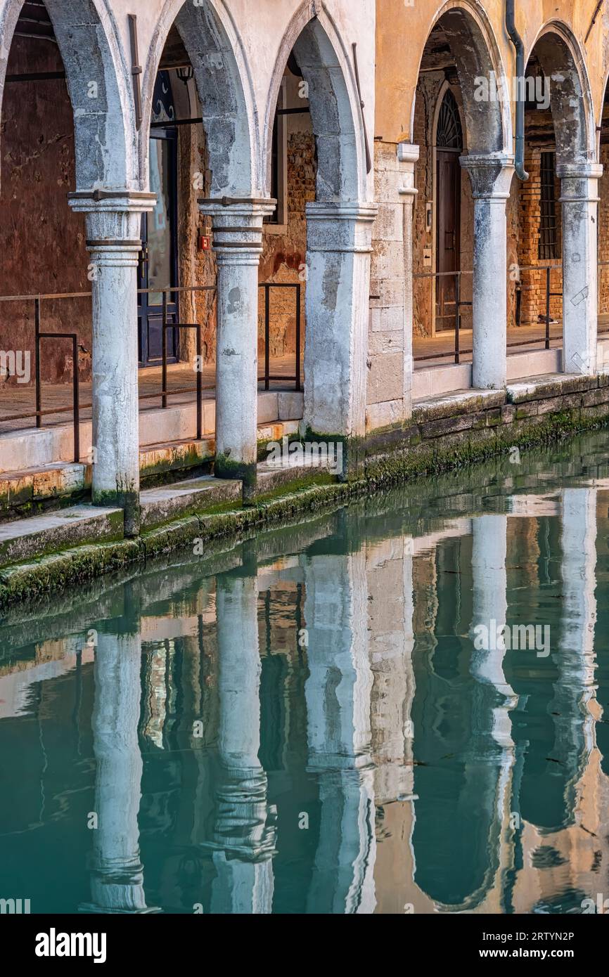 Détail architectural avec les colonnes en arc se reflétant dans les canaux d'eau de Venise, Italie. Banque D'Images